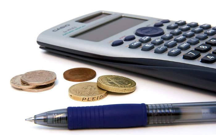 Imagem de calculadora e moeda ilustrando texto sobre "Fiz um empréstimo e não paguei. E agora?"